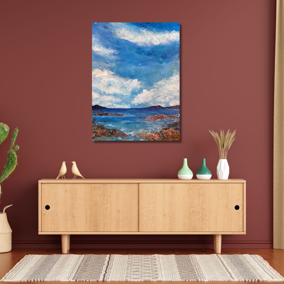 Original acrylic painting (18 by 24 inch) of a coastal scene with rocky shore and blue sky with clouds by Ottawa-based artist Mireille Laroche hung on a wall