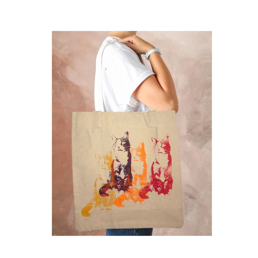 Person holding a tote bag with cat design on a beige background