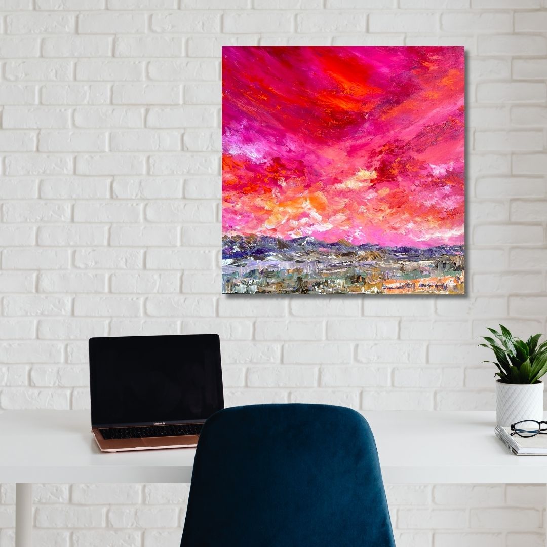 Colorful abstract painting by Ottawa-based artist Mireille Laroche on a white brick wall above a desk with a laptop and chair.