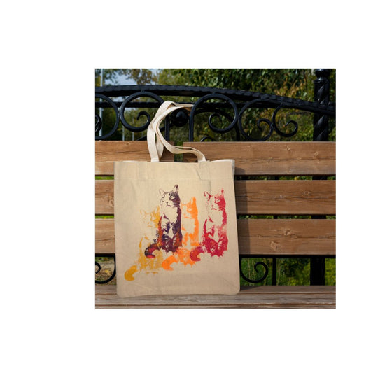 Tote bag with cat design hanging on a wooden bench outdoors