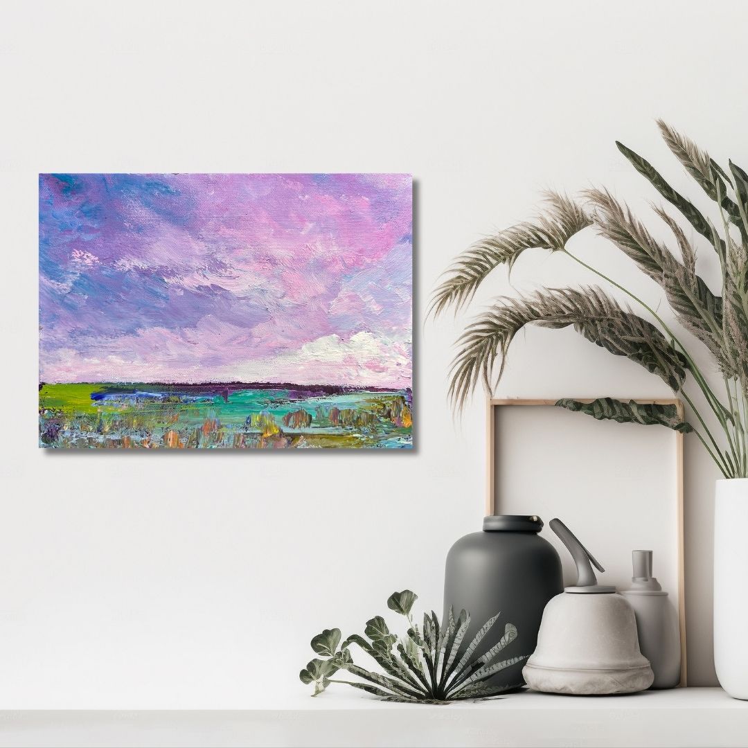Painting of an abstract  landscape with a purple sky  by Ottawa artist Mireille Laroche on a white wall above decorative items.