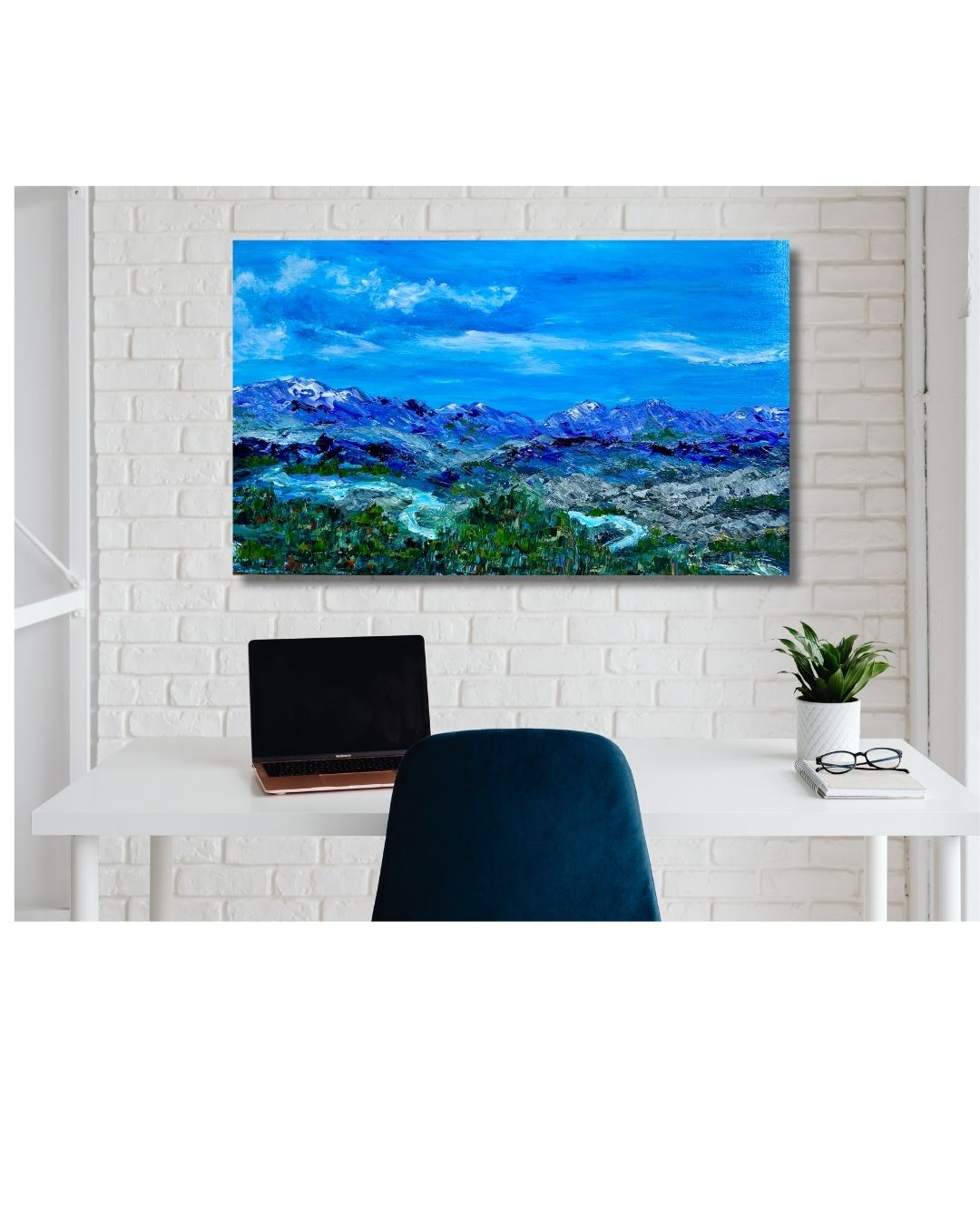 Depiction of a mountain landscape by Ottawa artist on a wall above a desk with a laptop.