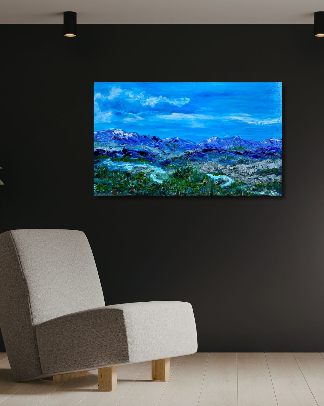 Modern living room with a gray armchair and a painting of a blue landscape by Ottawa artist Mireille Laroche on a black wall.