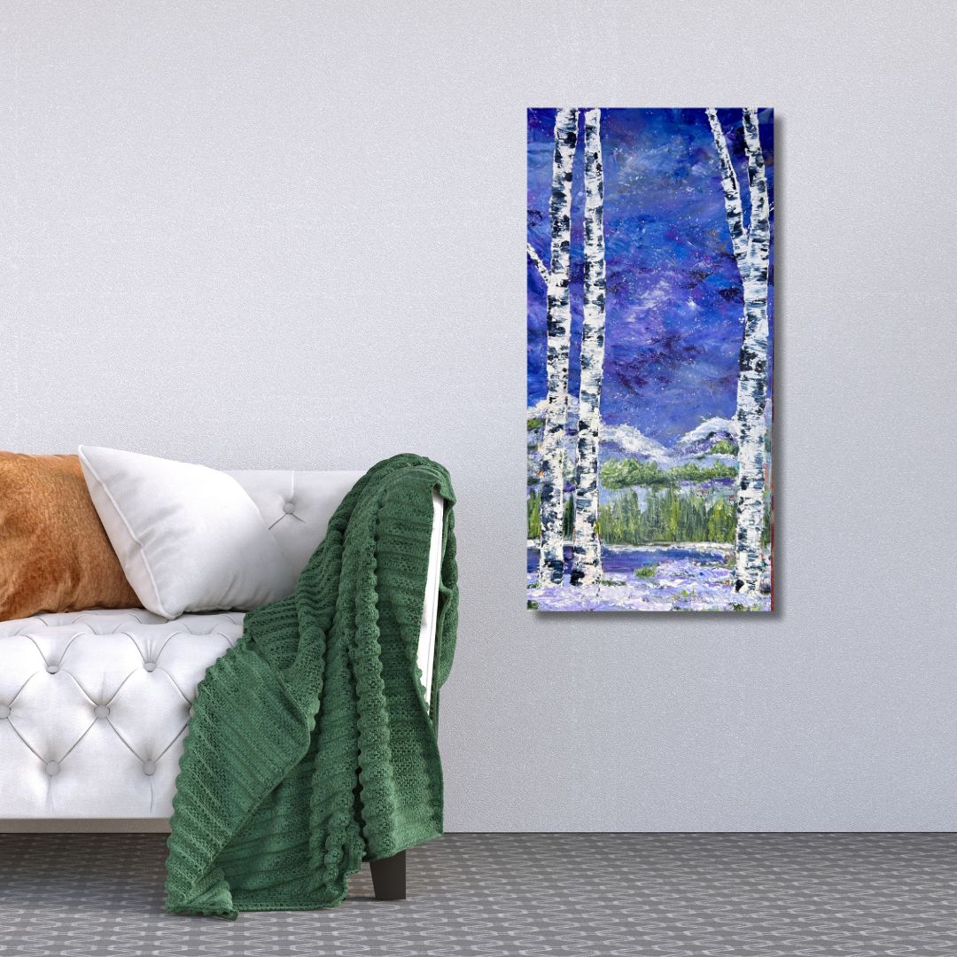 Painting of birch trees and a lake on a wall above a bed with green blanket.