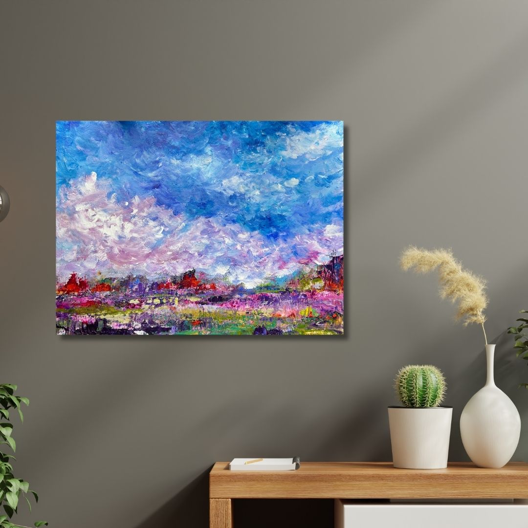 Colorful abstract landscape painting by Ottawa artist Mireille Laroche  on a gray wall above a wooden table with decorative items.