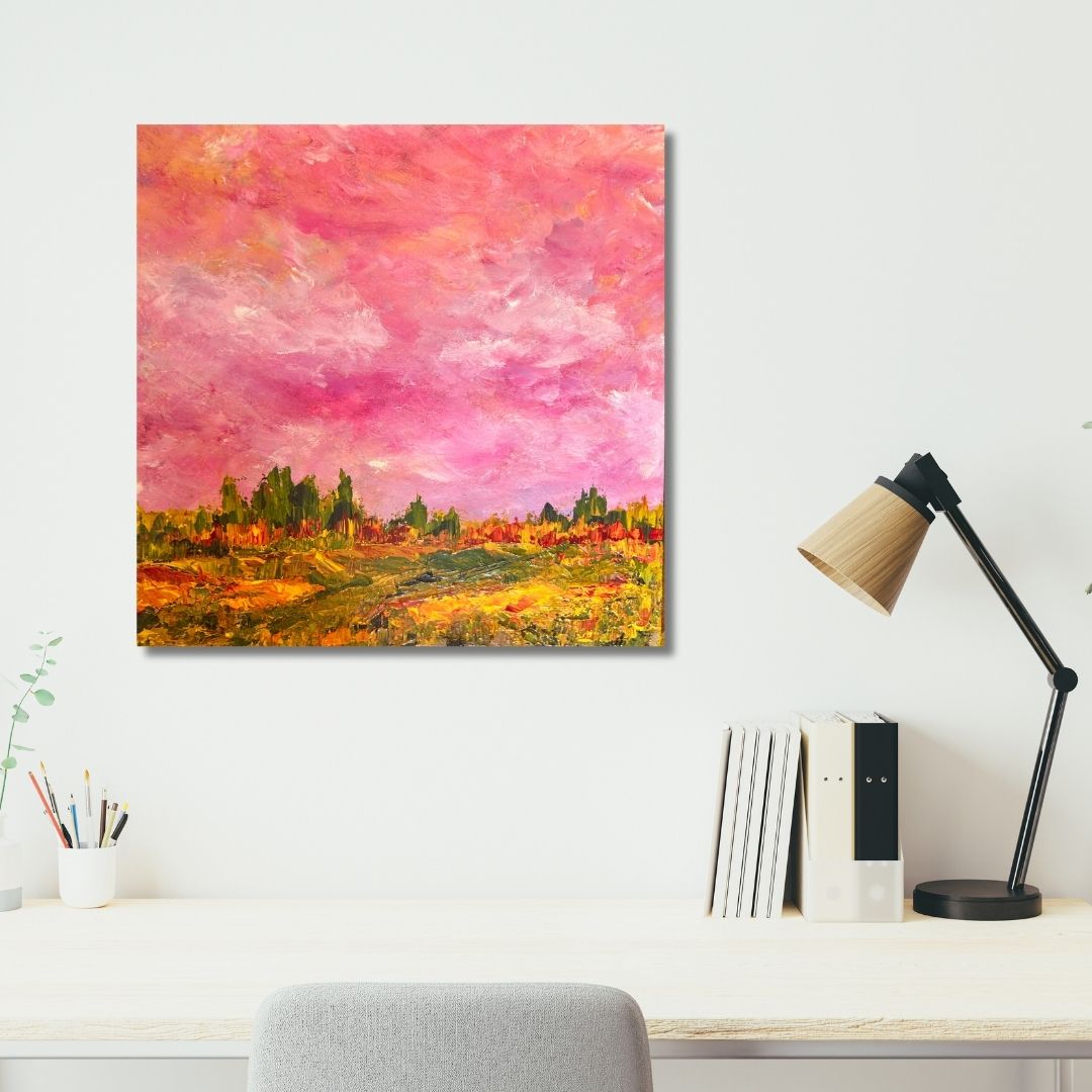 Abstract painting by Ottawa artist Mireille Laroche with pink and orange hues on a wall above a desk with a lamp and books.