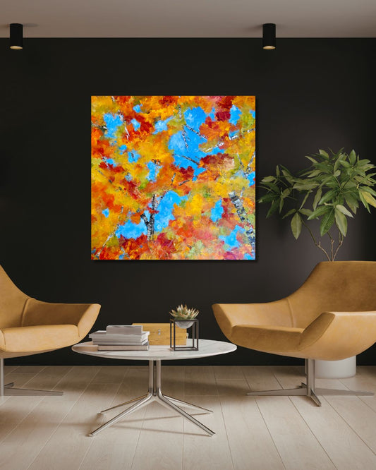 Original acrylic painting by Ottawa artist Mireille Laroche depicting tree tops over a blue sky. Painting on a black wall above chairs, a table and a plant. 
