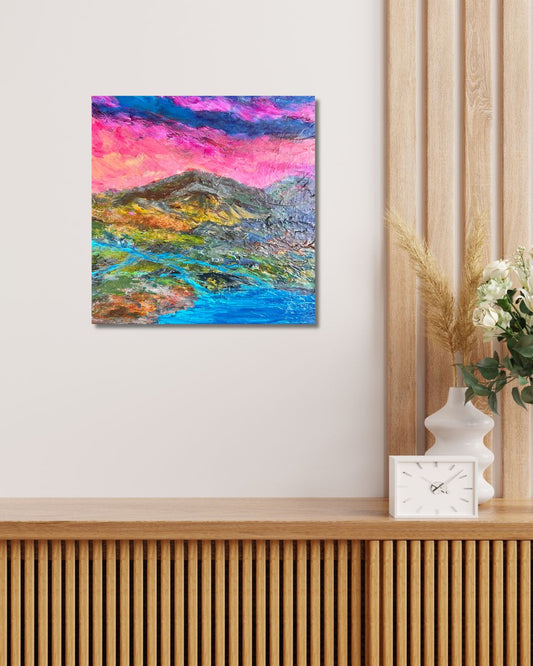 A colorful abstract landscape artwork by Ottawa artist Mireille Laroche, hanging on a light beige wall above a wooden slatted console table. The artwork features vibrant pink, purple, blue, green, and yellow brushstrokes.