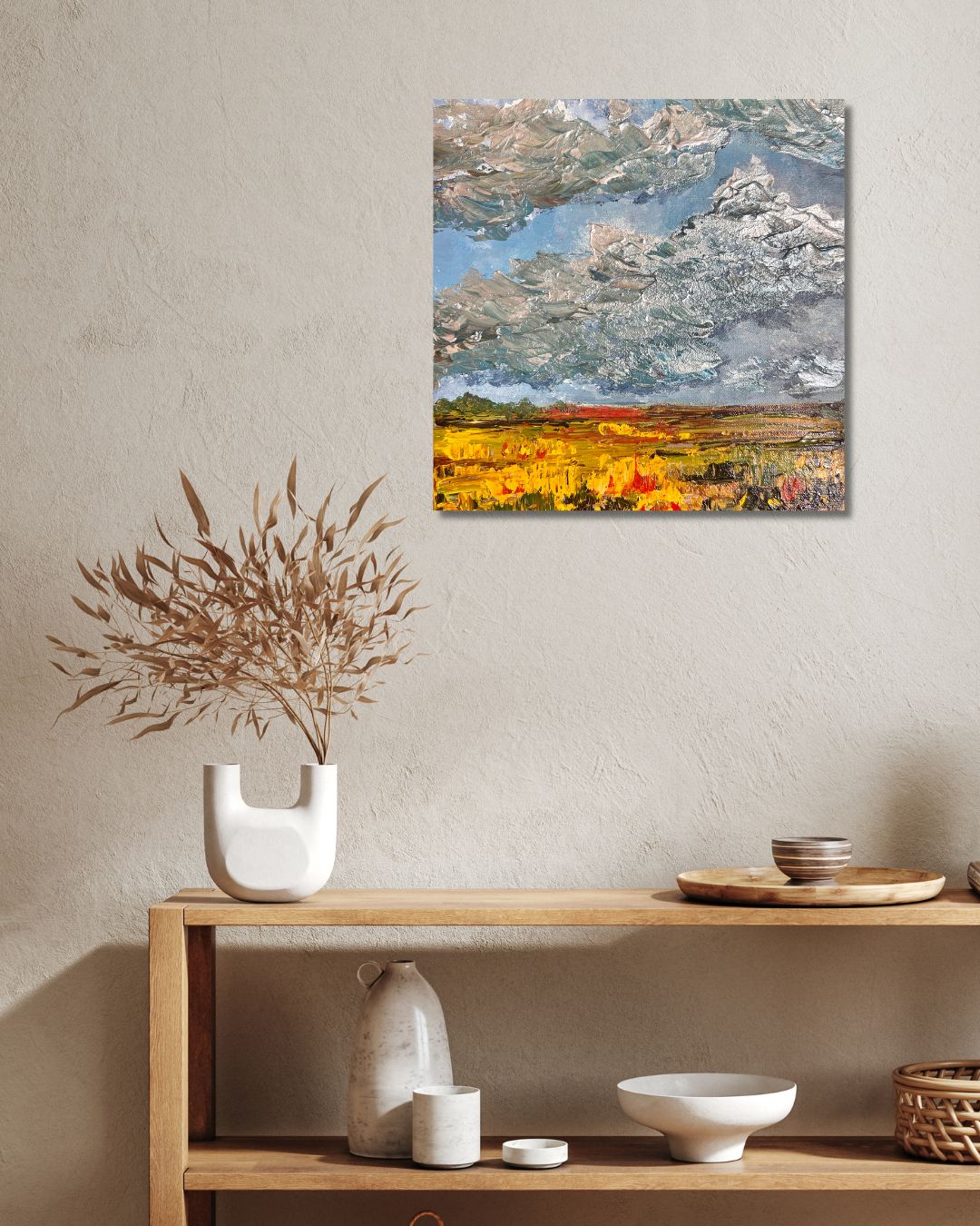Semi-abstract acrylic by Ottawa artist Mireille Laroche depicting silver clouds over the Prairies.  Painting on a beige wall over shelves with various decorative items on them